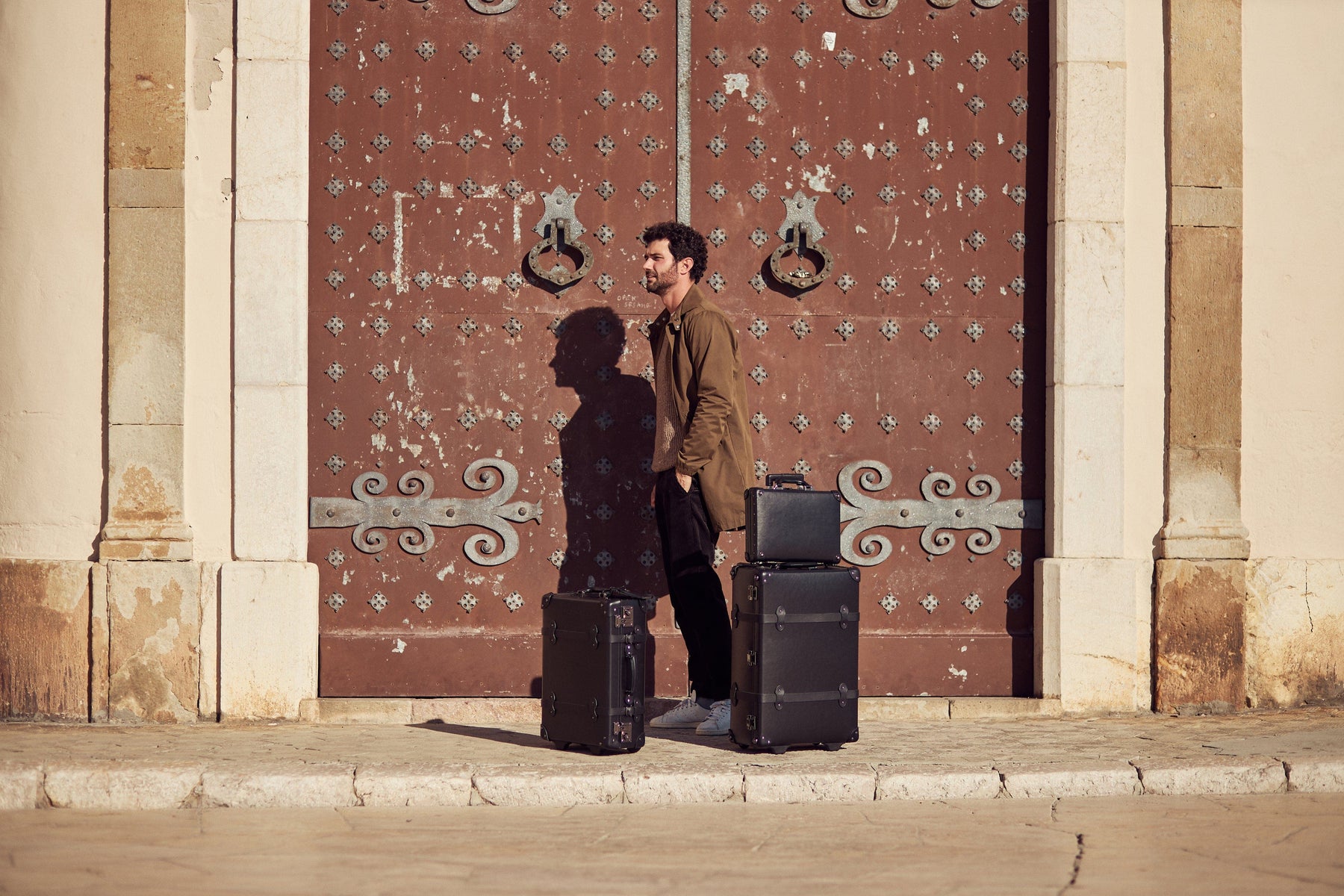 Lifestyle image of male model with The Industrialist fibreboard suitcases in  black