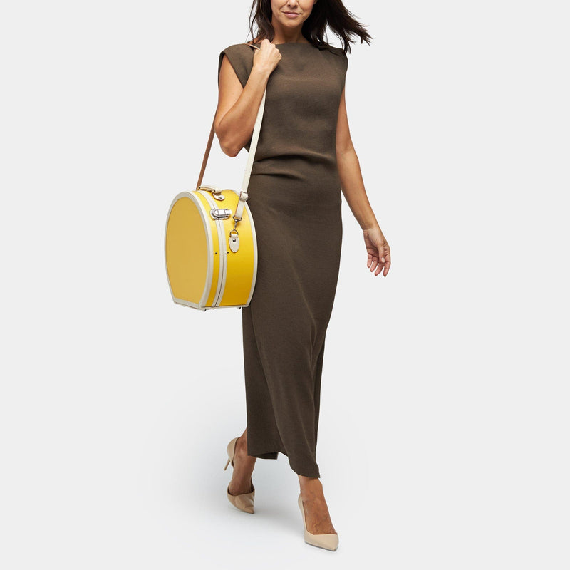 Model with the large hatbox Correspondent fibreboard suitcase in canary yellow with shoulder attachment strap