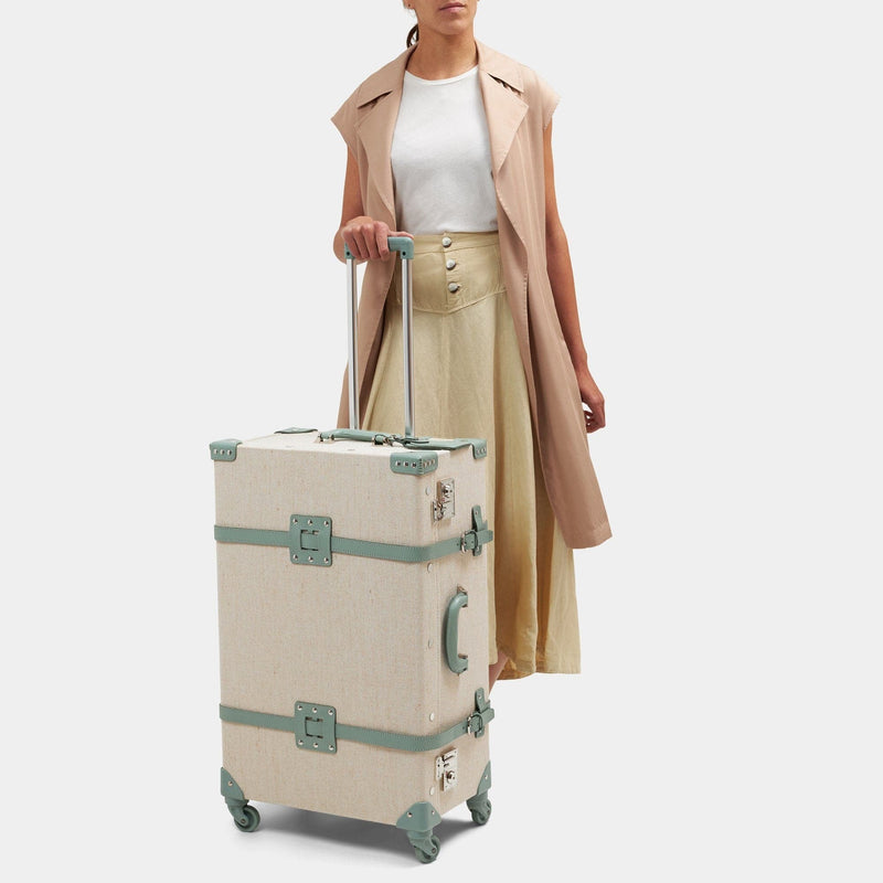 Model with the check-in spinner Editor linen suitcase with sea green trims and raised handle