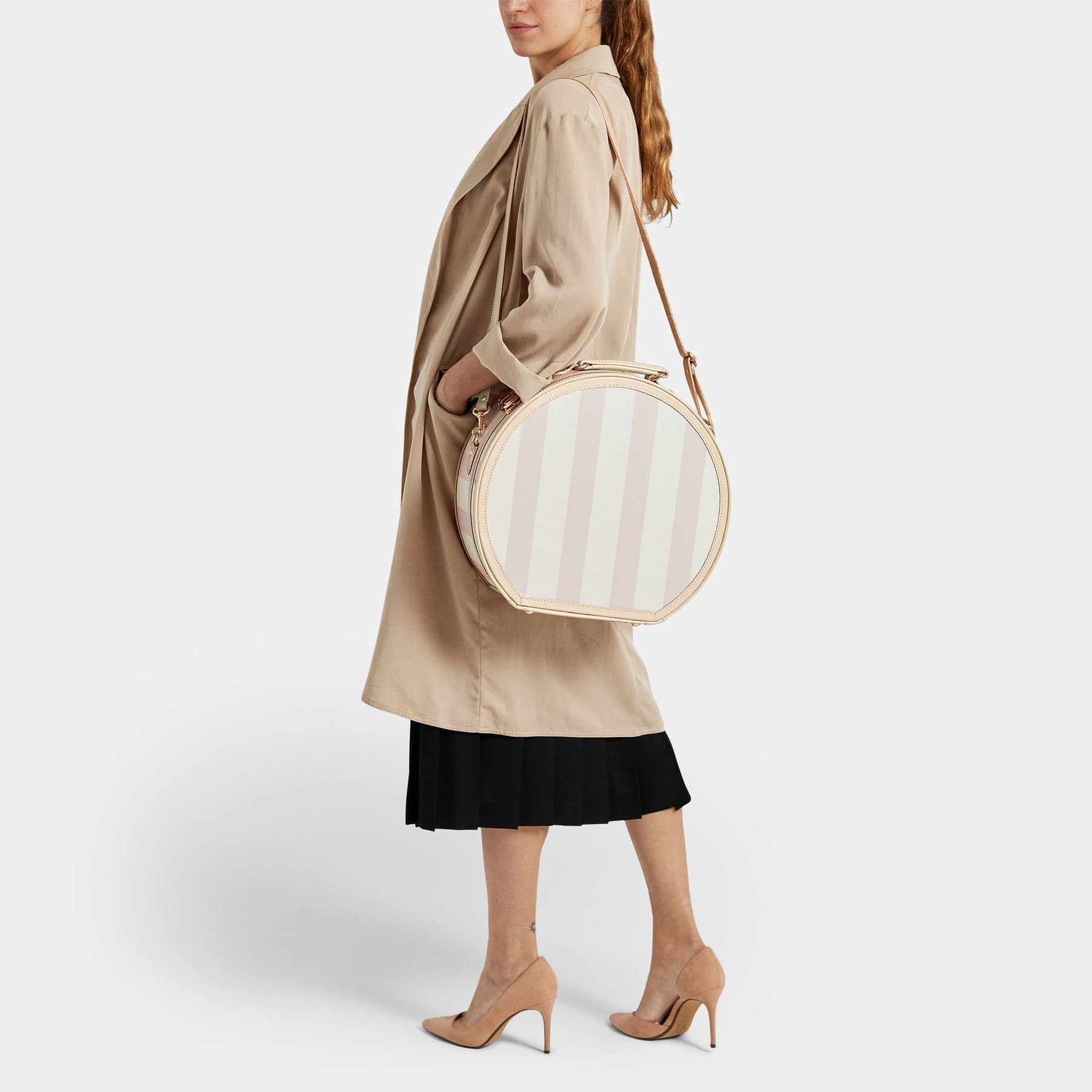 Model with the large hatbox Illustrator fibreboard suitcase in pink-stripe with shoulder attachment strap