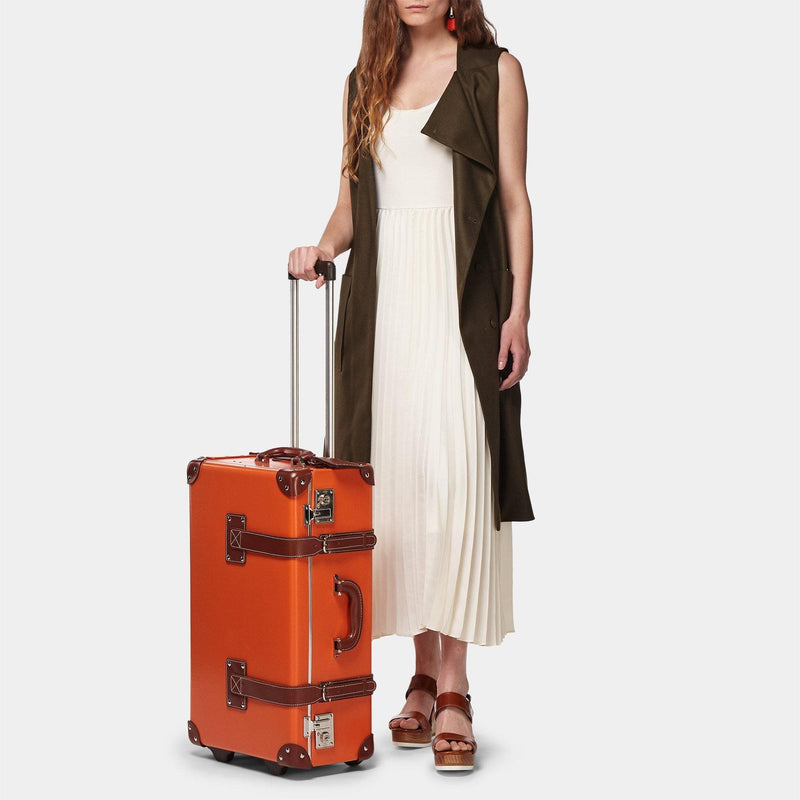 Model with the stowaway Anthropologist leather suitcase in orange with raised handle