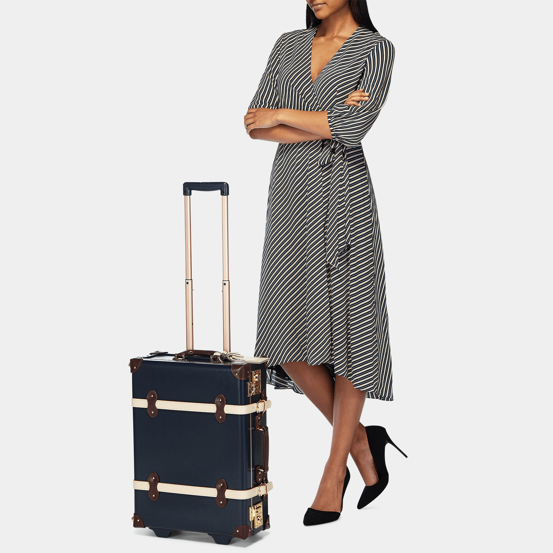 Model with the carry-on Architect leather suitcase in navy with raised handle