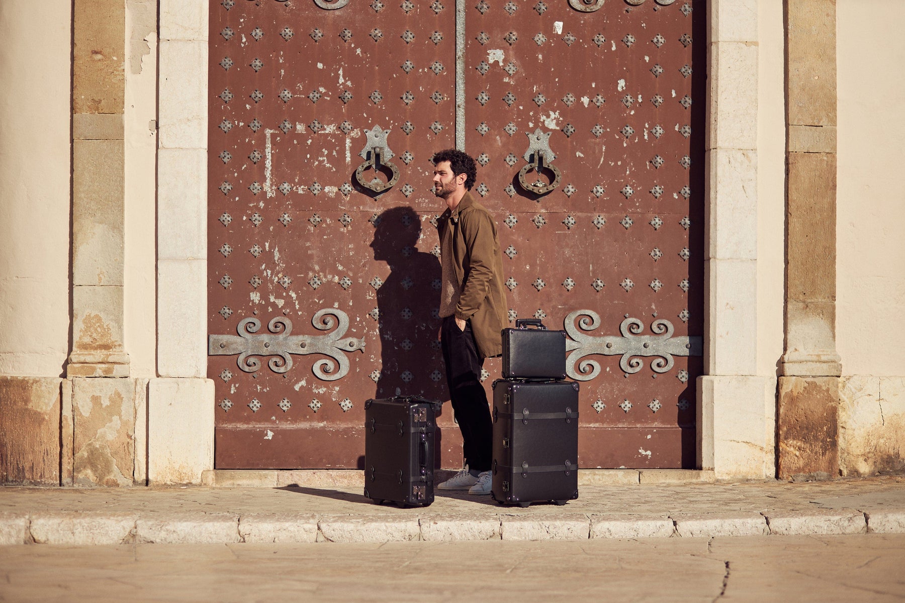 Lifestyle image of male model with The Industrialist fibreboard suitcases in  black 