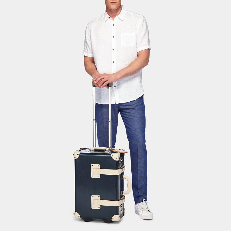 Male model with the carry-on Anthropologist leather suitcase in navy with raised handle