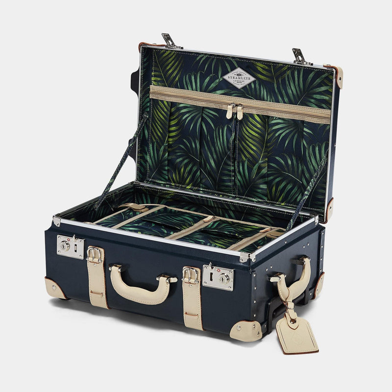 Open product view of the carry-on Anthropologist leather suitcase in navy with green palms print lining and cream leather luggage tag
